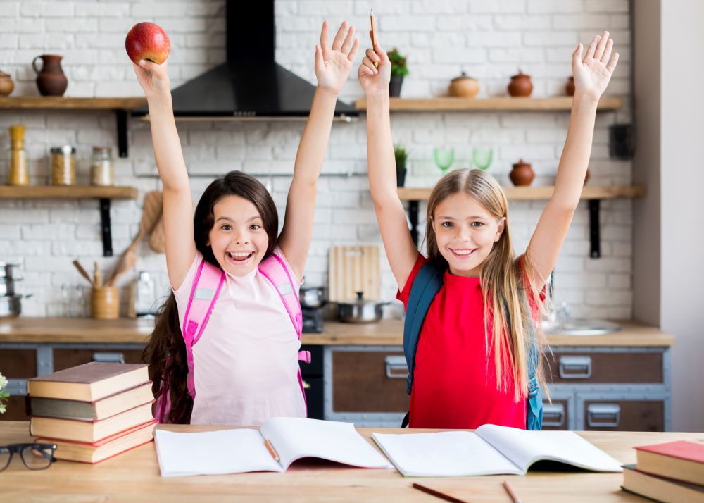 Two smiling schoolgirls with backpacks and books, ready for a new school year